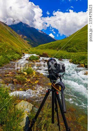 Camera on tripod capturing mountain stream in serene landscape 135476825