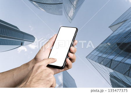 Smartphone Mockup in Hands Against Modern City Skyscrapers 135477375