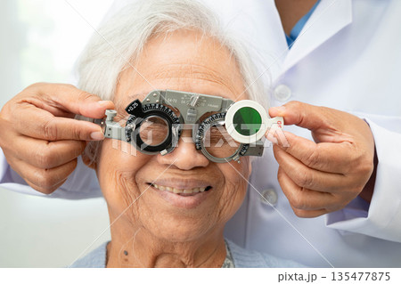 Asian senior woman wearing ophthalmic vision eye test and using optical trial frame. Asian senior woman wearing ophthalmic vision eye test and using optical trial frame. 135477875