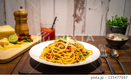 木製のテーブルに置かれた本格的なミートソースパスタ（ボロネーゼ）と食材の風景 135477897