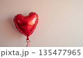 A balloon in the form of a red heart on a light background with a place for text. 135477965