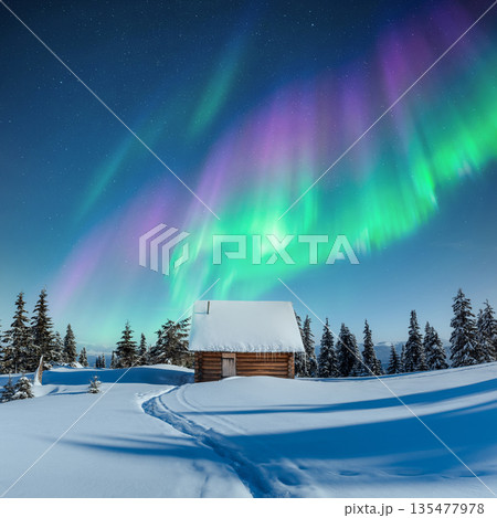 Cozy wooden hut in snowy mountains under incredible Northern lights 135477978