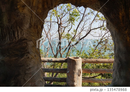 View from the cave to the sea.View from a stone cave of blue sky, turquoise sea and garden. View from the cave to the sea.View from a stone cave of blue sky, turquoise sea and garden. 135478988