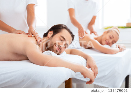 Relaxed Husband And Wife Receiving Relaxing Back Massage During Body Relaxation Therapy Lying On Beds Indoor, With Eyes Closed. Luxury Spa Service Advertisement, Beauty And Wellness. Selective Focus Relaxed Husband And Wife Receiving Relaxing Back Massage During Body Relaxation Therapy Lying On Beds Indoor, With Eyes Closed. Luxury Spa Service Advertisement, Beauty And Wellness. Selective Focus 135479091