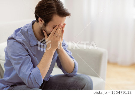 Male Depression. Frustrated Man Crying Covering Face Sitting On Sofa At Home. Desperate Guy Cries In Living Room. Unhappiness And Stressful Modern Life Concept. Empty Space For Text 135479112