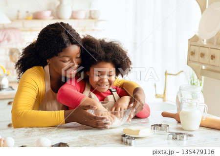Happy Family In Kitchen. Black Mother And Little Daughter Preparing Dough Together, Loving African American Mom Teaching Her Child Cooking And Baking Homemade Pastry, Enjoying Spending Time With Kid Happy Family In Kitchen. Black Mother And Little Daughter Preparing Dough Together, Loving African American Mom Teaching Her Child Cooking And Baking Homemade Pastry, Enjoying Spending Time With Kid 135479116