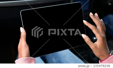Modern remote work, online map, travel route in trip. Young african american lady holds tablet with empty screen in hands, surfing on internet and sits in car, cropped, pov, close up, free space 135479256