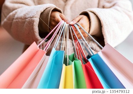 Shopping Spree Concept. Closeup of unrecognizable african american lady holding many colorful bags and showing it to camera. Black female shopper carrying purchases and gifts. Retail And Sale 135479312