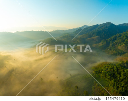 Aerial view of flowing fog waves on mountain tropical rainforest,Bird eye view image over the clouds Amazing nature background with clouds and mountain peaks in Thailand 135479410