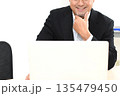 ノートPCを見る笑顔のスーツ姿の中年男性 135479450
