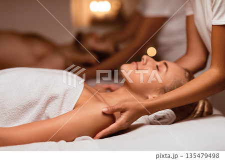 Wife And Husband Enjoying Relaxing Massage During Couples Beauty Procedure Lying With Eyes Closed Resting At Luxury Spa Center. Relaxation And Wellness. Selective Focus, Low Light. 135479498