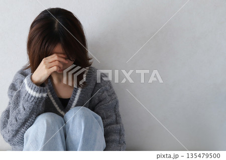 目を覆って落ち込む女性の後ろ姿 135479500