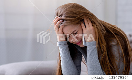 Sad young woman having conversation on mobile phone and crying at home. Millennial lady having difficult talk, hearing sad news, going through breakup or relationship problems 135479594