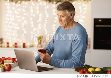 Lonely Christmas. Sad Senior Man At Laptop Making Video Call And Drinking Wine Celebrating New Year Holidays Alone At Home. Quarantine Xmas Holiday Celebration During Covid-19 Coronavirus Pandemic 135479646