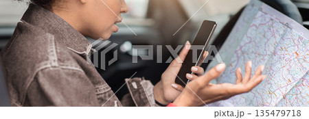 No connection and error in location, modern gadgets and online map. Sad millennial african american female got lost on road, sits in car with chart, looks at smartphone and spreads her arms, profile No connection and error in location, modern gadgets and online map. Sad millennial african american female got lost on road, sits in car with chart, looks at smartphone and spreads her arms, profile 135479718