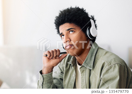 Pensive black teen guy in headphones passing difficult exam on laptop, thinking about his answer at home, space for design on PC screen. Teenage student studying remotely, taking test on web 135479770