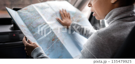Search for road, found route and travel with friends in city. Busy beautiful cute young african american woman driver researching map in car and think, view of window with raindrops, copy space 135479925