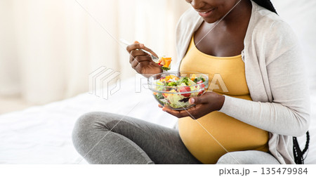 Happy Black Pregnant Woman Holding Bowl With Fresh Vegetable Salad, Enjoying Healthy Nutrition, Having Organic Vegetarian Meal For Lunch, Sitting On Bed At Home, Closeup Shot With Free Space Happy Black Pregnant Woman Holding Bowl With Fresh Vegetable Salad, Enjoying Healthy Nutrition, Having Organic Vegetarian Meal For Lunch, Sitting On Bed At Home, Closeup Shot With Free Space 135479984