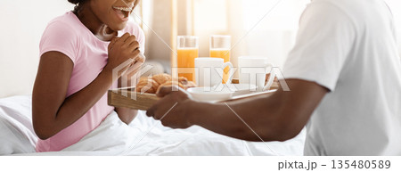 Romantic african american husband bringing breakfast in bed for his excited wife, bedroom interior, empty space. Black man waking up his girlfriend with fresh tasty breakfast, weekend at home Romantic african american husband bringing breakfast in bed for his excited wife, bedroom interior, empty space. Black man waking up his girlfriend with fresh tasty breakfast, weekend at home 135480589
