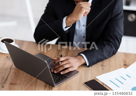 Cropped of black businessman in suit working with laptop in office, checking marketing report, modern technologies in business concept. Unrecognizable african american manager, CEO using computer Cropped of black businessman in suit working with laptop in office, checking marketing report, modern technologies in business concept. Unrecognizable african american manager, CEO using computer 135480832