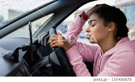 Waiting for client call, stopping in traffic jam and breakdown on road, not again. Tired sad millennial african american female with closed eyes leans on steering wheel and waits for move, copy space Waiting for client call, stopping in traffic jam and breakdown on road, not again. Tired sad millennial african american female with closed eyes leans on steering wheel and waits for move, copy space 135480878