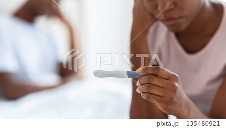 Unrecognizable black woman sitting on bed and holding positive pregnancy test, african american man in bed on background, unintended pregnancy concept, cropped, panorama. Selective focus on test 135480921