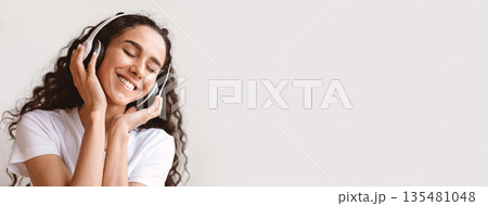 Joyful young brunette woman in headphones listening to music while resting on sofa at home, copy space. Happy lady with closed eyes enjoying beautiful music, stress relief, closeup portrait Joyful young brunette woman in headphones listening to music while resting on sofa at home, copy space. Happy lady with closed eyes enjoying beautiful music, stress relief, closeup portrait 135481048