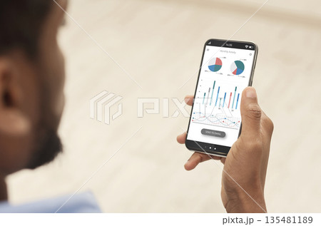 Cropped of black man using analytics mobile app on smartphone, checking his incomes on trading stocks, panorama. Male hands holding phone with newest analytics mobile application 135481189