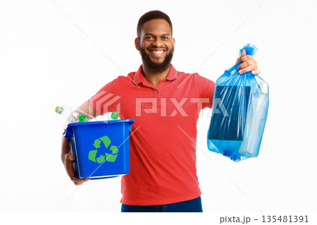Black Man Holding Box With Recycling Plastic Litter And Blue Garbage Bag Standing On White Studio Background, Smiling To Camera. Waste Sorting And Recycling Concept Black Man Holding Box With Recycling Plastic Litter And Blue Garbage Bag Standing On White Studio Background, Smiling To Camera. Waste Sorting And Recycling Concept 135481391
