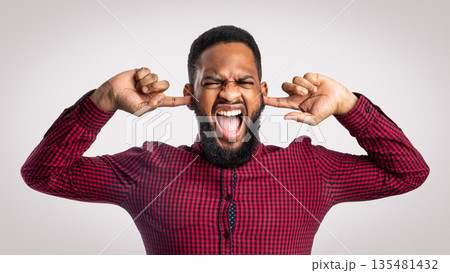 Mad Black Man Shouting Covering Ears With Hands And Closing Eyes Posing Over White Background In Studio. Negative Emotion, Madness And Stress. Too Loud Concept 135481432
