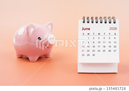 Desk calendar for June 2026 and pink piggy bank. Desk calendar for June 2026 and pink piggy bank. 135481728
