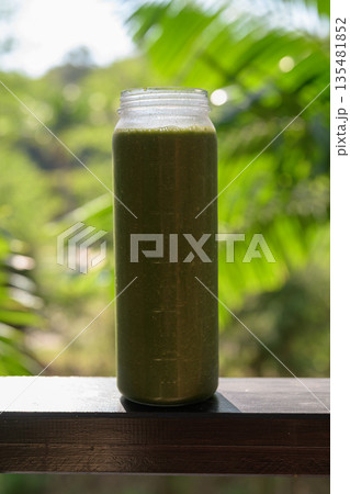 Green Smoothie Bottle with Tropical Leaves Background for Healthy Lifestyle Concept 135481852