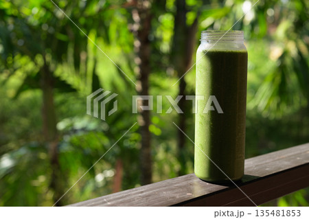Green Smoothie Bottle with Tropical Leaves Background for Healthy Lifestyle Concept 135481853