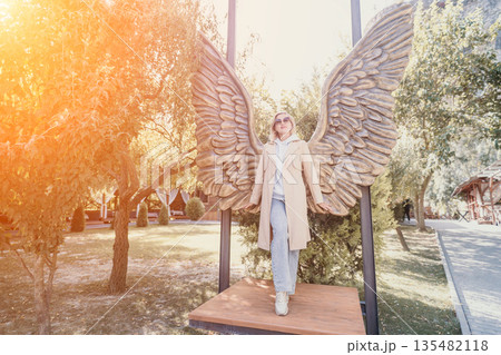 Woman Standing Underneath Angel Wings Sculpture 135482118