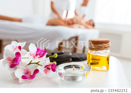 Couples Massage Spa Composition With Stones, Bottle Of Body Oil, Candle And Orchid Flowers Lying On Desk In Beauty Salon. Romanitc Honeymoon Vacation, Luxury Body Care And Relaxation. Selective Focus Couples Massage Spa Composition With Stones, Bottle Of Body Oil, Candle And Orchid Flowers Lying On Desk In Beauty Salon. Romanitc Honeymoon Vacation, Luxury Body Care And Relaxation. Selective Focus 135482251