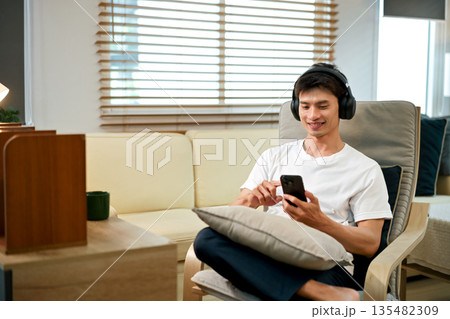 Relaxed man listening to music at home with headphones Relaxed man listening to music at home with headphones 135482309