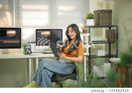 Professional female video editor editing video on his digital tablet in home office studio Professional female video editor editing video on his digital tablet in home office studio 135482418