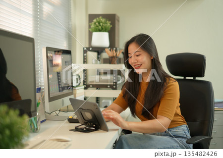 Professional female video editor editing video on his digital tablet in home office studio Professional female video editor editing video on his digital tablet in home office studio 135482426