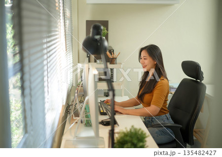 Creative young woman working on laptop in her studio Creative young woman working on laptop in her studio 135482427