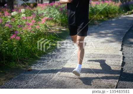 Cropped shot man jogging on a garden pathway Cropped shot man jogging on a garden pathway 135483581