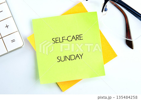 A light green sticky note with the words Self-Care Sunday is stacked upon yellow sticky notes, beside a white calculator and pair of glasses. Its a call for relaxation 135484258