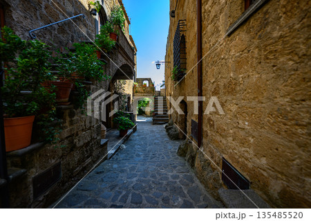 Picturesque medieval-style passageway with stone paving, stairs, and warm sunlight. Authentic old town atmosphere with no people. Picturesque medieval-style passageway with stone paving, stairs, and warm sunlight. Authentic old town atmosphere with no people. 135485520