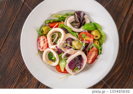 Mediterranean squid salad with arugula olives and tomatoes on white ceramic plate Mediterranean squid salad with arugula olives and tomatoes on white ceramic plate 135485630