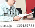 商談中に書類を確認する作業服姿の中年男性 135485783