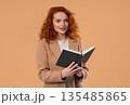 Ginger businesswoman or student reading book with smile on beige. Discovery time 135485865