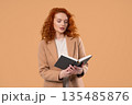 Ginger businesswoman or student reading book with smile on beige. Discovery time 135485876