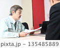 商談中に書類を確認する作業服姿の中年男性 135485889