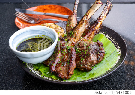 ラムチョップのグリル ミントソース添え バナナの葉に盛り付けられた肉料理 ラムチョップのグリル ミントソース添え バナナの葉に盛り付けられた肉料理 135486009