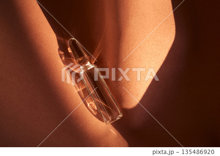 Glass ampoule on textured surface in sunlight Glass ampoule on textured surface in sunlight 135486920