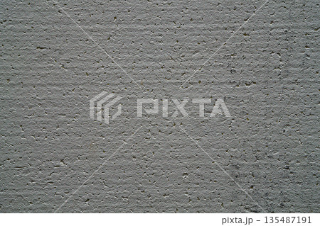 Cut surface of dark white foam sheet painted with water-based paint, the texture is created from sticky round parts with different diameters and pits, voids. The cut is uneven with waves 135487191